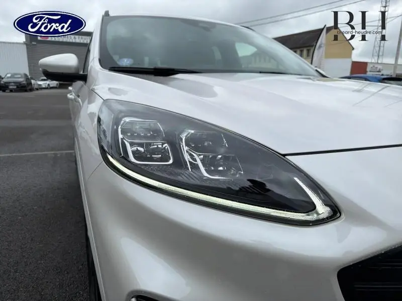 Gros plan sur le phare avant gauche du Ford Kuga 2023 en Premium Blanc Platinum, soulignant son design LED moderne.