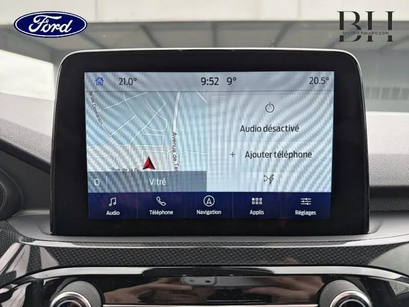 Écran tactile central du Ford Kuga 2023 affichant la navigation et options audio, intérieur noir moderne.