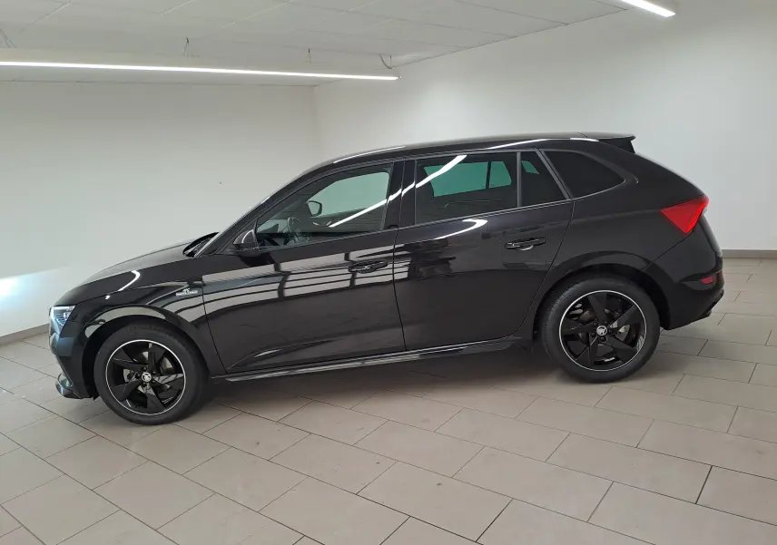 Vue latérale droite d'une Skoda Scala 1.0 TSI Monte-Carlo noire nacrée, avec jantes noires et intérieur visible.