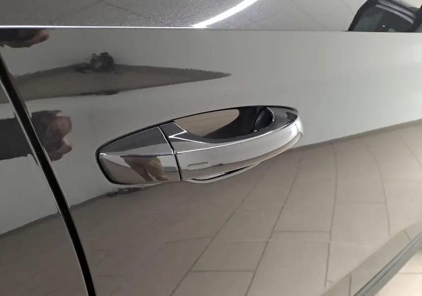 Poignée de porte chromée en gros plan sur la portière côté gauche d'une Skoda Scala 2022 noir Magic nacré.