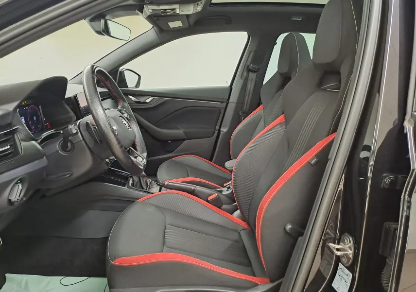 Intérieur avant droit d'une Skoda Scala 2022 noir nacré avec sièges sport noirs soulignés de rouge et volant cuir.