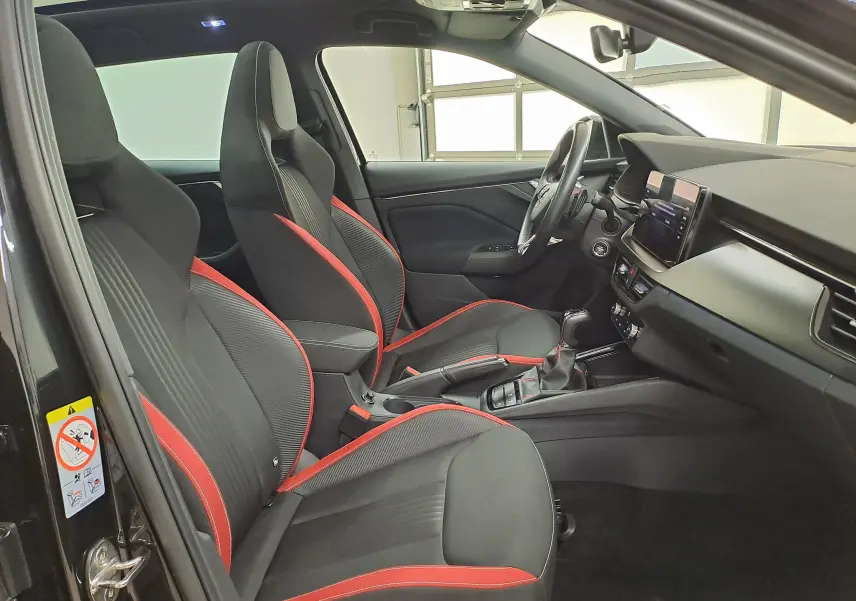 Vue intérieure côté gauche de la Skoda Scala 2022 avec sièges sport noirs et surpiqûres rouges, tableau de bord moderne.