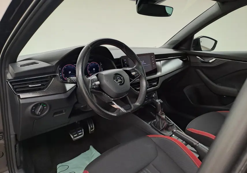 Intérieur du Skoda Scala 1.0 TSI Monte-Carlo 2022, vue côté conducteur, sièges noirs avec surpiqûres rouges et tableau de bord moderne.