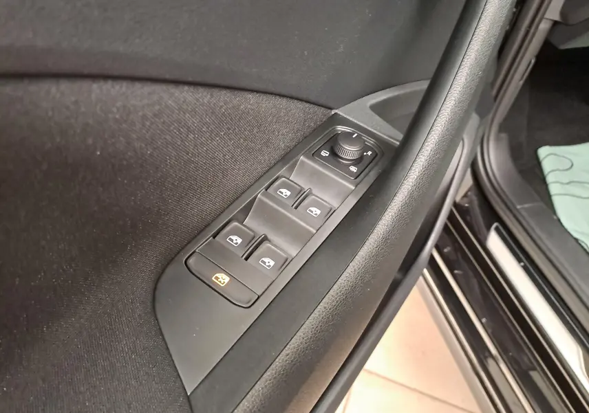 Gros plan sur les commandes des vitres et rétroviseurs côté gauche d'une Skoda Scala 1.0 TSI noire nacrée.