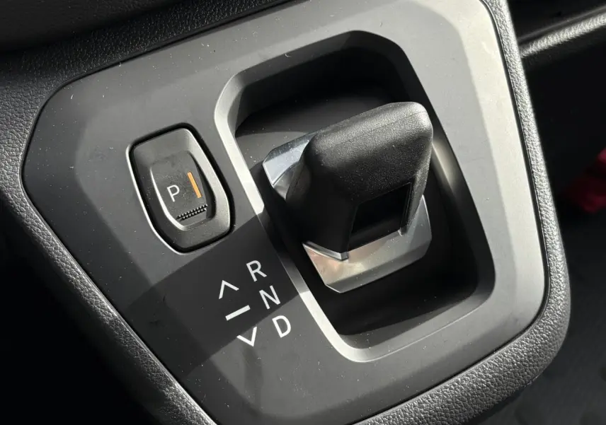 Gros plan sur la commande de boîte automatique noire du Renault Trafic Fourgon blanc, avec bouton parking éclairé.