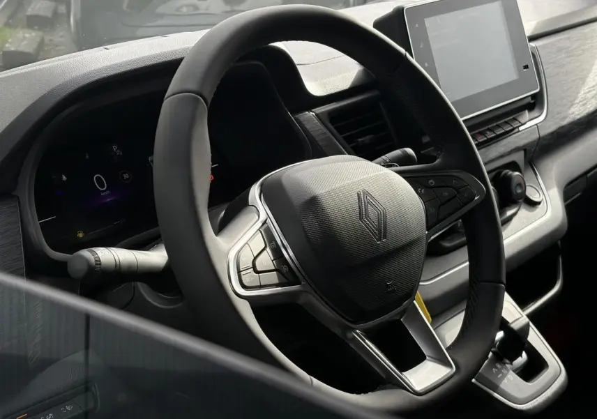 Vue rapprochée du volant et du tableau de bord numérique du Renault Trafic Fourgon blanc Glacier, avec écran tactile central.