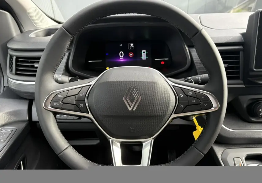 Vue rapprochée du volant multifonction noir avec logo Renault et tableau de bord numérique du Trafic Fourgon blanc.