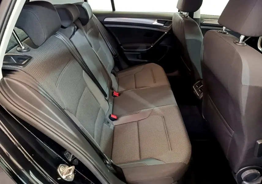 Vue intérieure côté gauche sur la banquette arrière grise d’une Volkswagen Golf noire, avec ceintures de sécurité visibles.