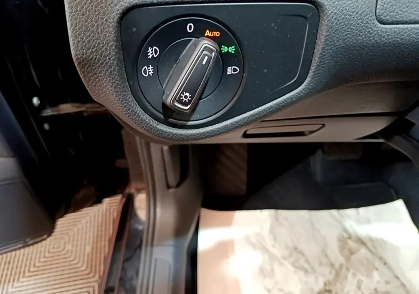 Gros plan sur la molette de réglage des phares dans l'habitacle d'une Volkswagen Golf noire 2019.