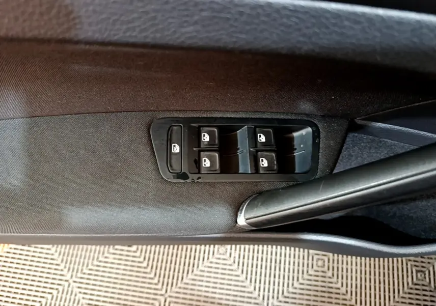 Gros plan sur les commandes des vitres électriques côté conducteur d’une Volkswagen Golf noire de 2019.