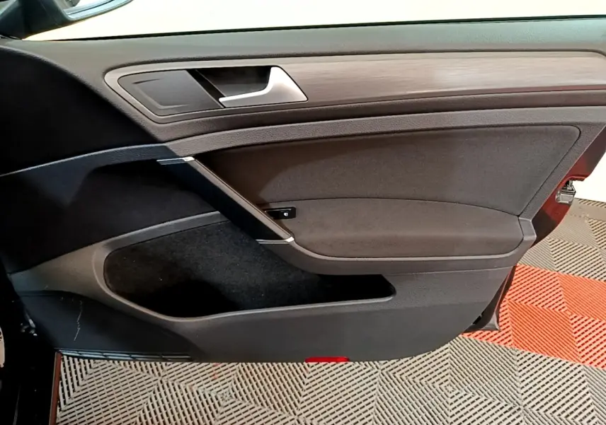 Vue intérieure de la porte avant gauche noire de la Volkswagen Golf 2019 avec insert bois et poignée argentée.
