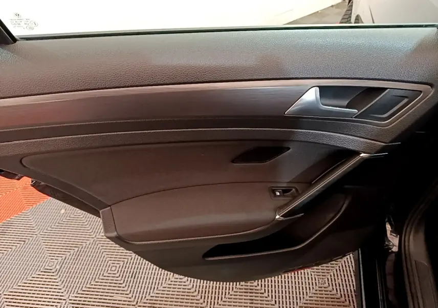 Vue intérieure de la porte avant droite noire de la Volkswagen Golf 2019 avec insert imitation bois et poignée argentée.