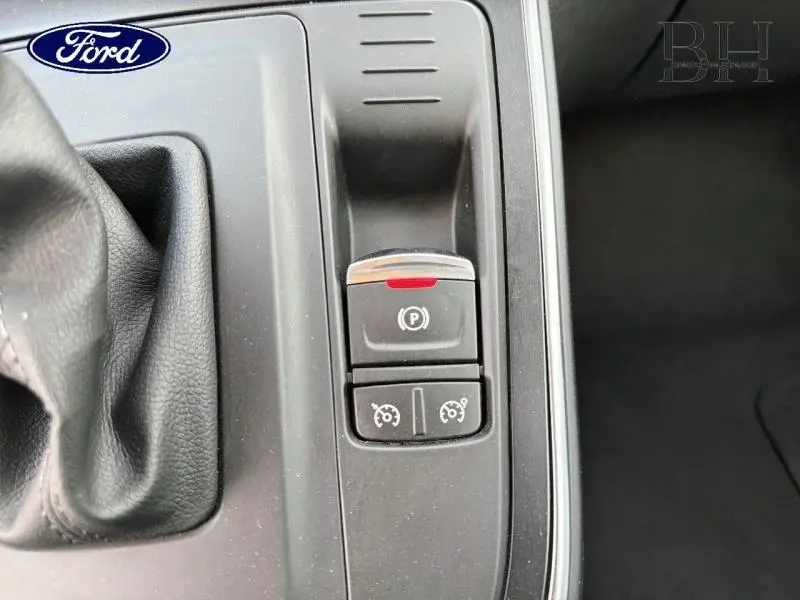 Gros plan sur la console centrale noire avec commandes de frein à main électrique et régulateur de vitesse.