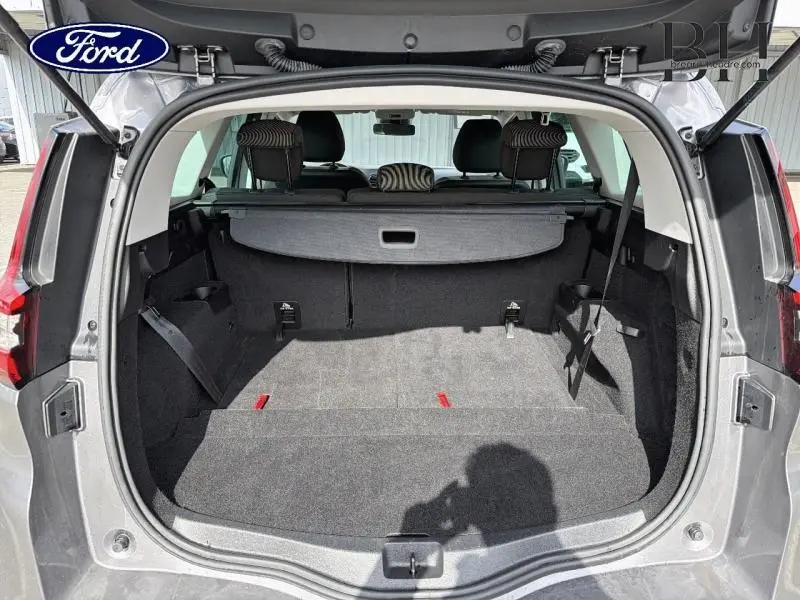 Vue arrière du coffre ouvert du Renault Grand Scenic gris Cassiopée, montrant la tablette cache-bagages et les sièges arrière.