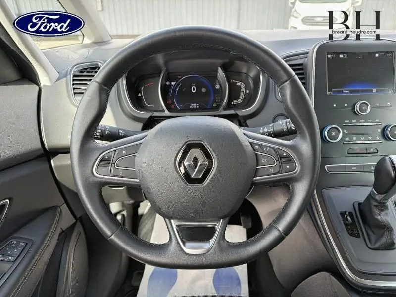 Vue intérieure centrée sur le volant cuir du Renault Grand Scenic 2019 avec tableau de bord numérique et console centrale grise.