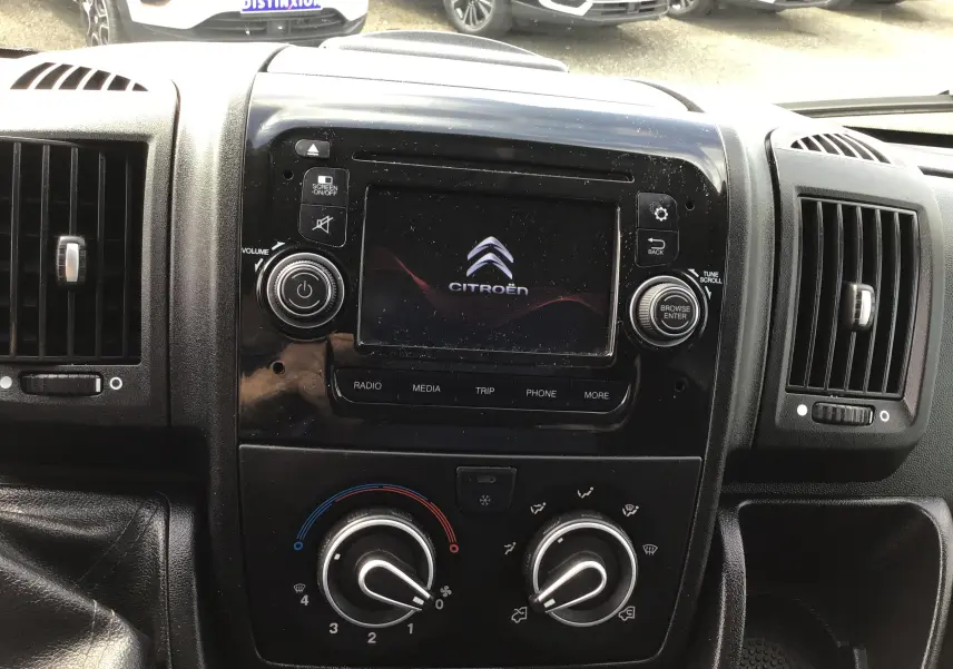 Tableau de bord noir du Citroën Jumper gris, avec écran central affichant le logo Citroën et commandes climatisation visibles.