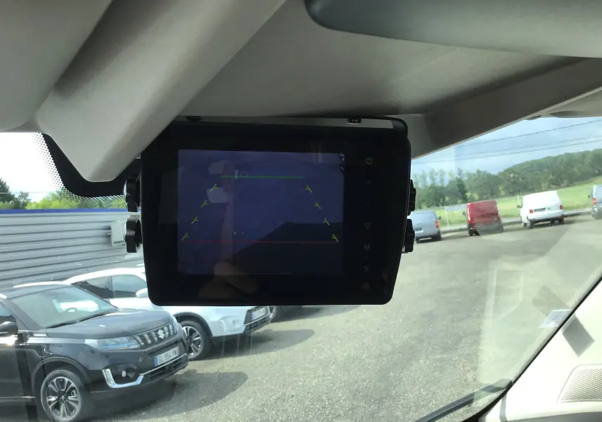 Écran de caméra de recul à l'intérieur d'un Citroën Jumper Food Truck gris, vue avant sur parking extérieur.