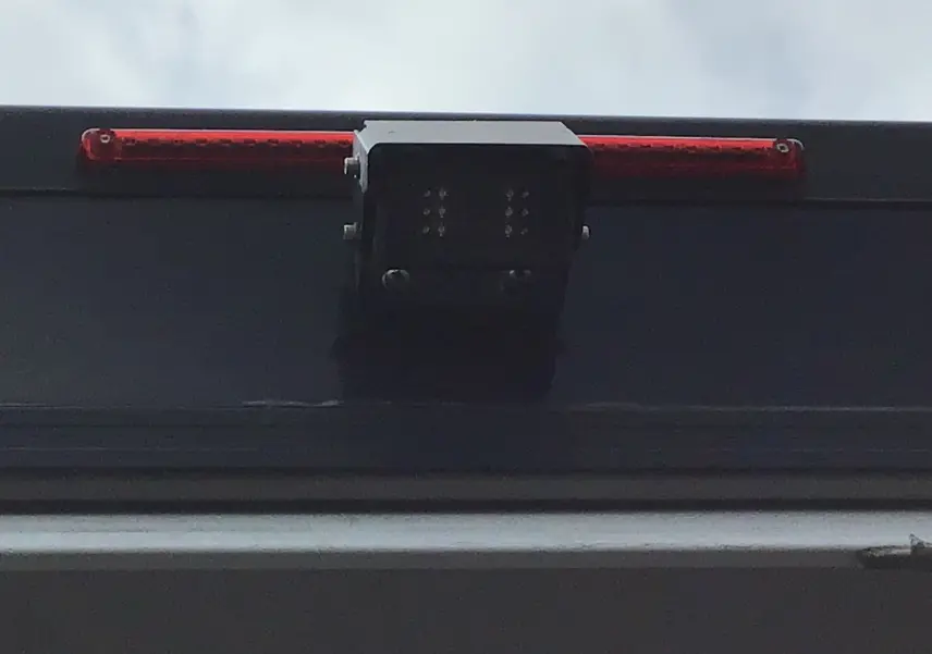 Gros plan sur la caméra de recul et le feu stop supérieur du Citroën Jumper gris Graphito, arrière du véhicule.