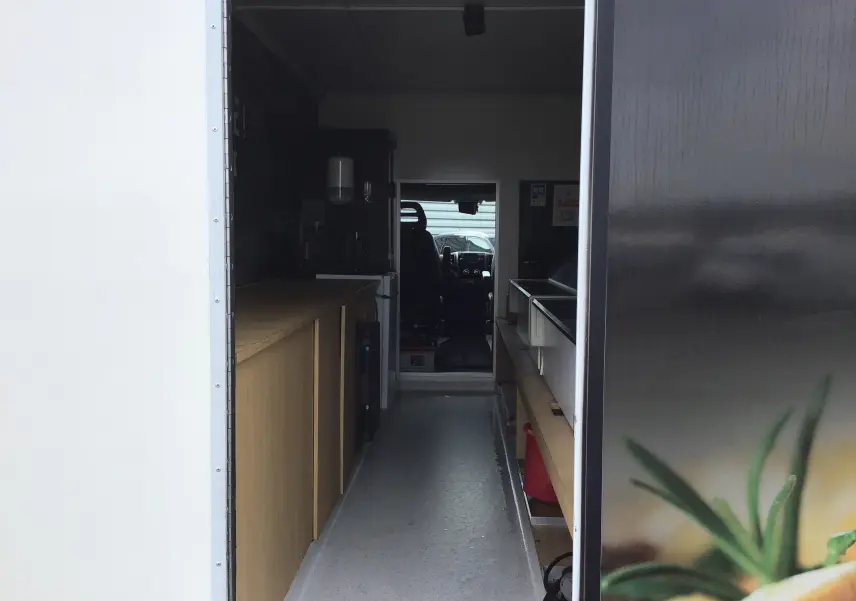 Vue intérieure en perspective du food truck gris graphito Citroën Jumper, montrant l'aménagement avec plan de travail et vitrines réfrigérées.