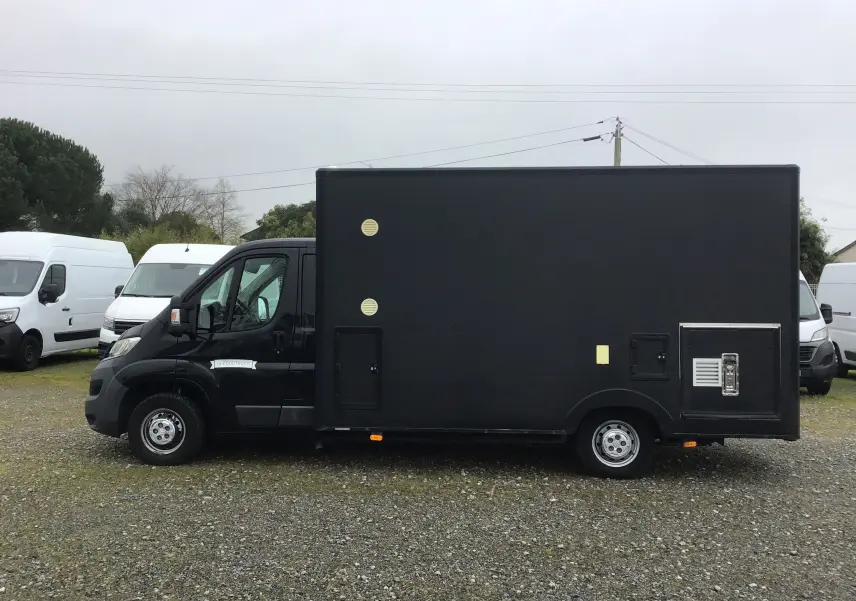 Vue latérale gauche d'un Citroën Jumper plancher cabine gris graphito aménagé en food truck avec caisse magasin noire.
