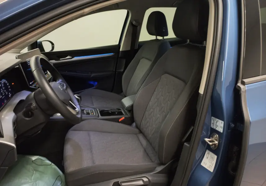Vue intérieure côté conducteur d'une Volkswagen Golf 1.5 TSI 116 BVM6 VW Edition bleu anemone, sièges tissu gris et éclairage d'ambiance bleu