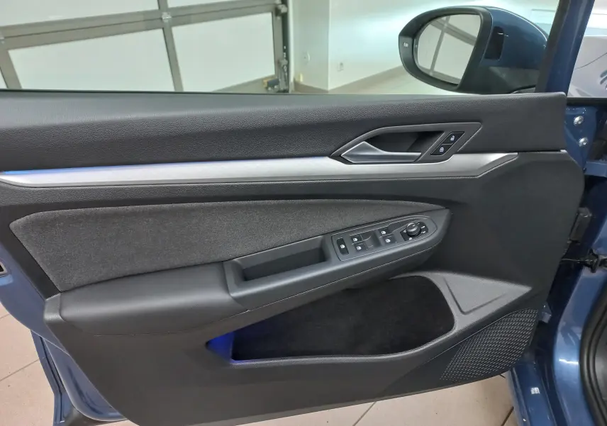 Vue rapprochée de la porte avant gauche de la Volkswagen Golf Bleu Anemone avec commandes électriques et garniture noire.