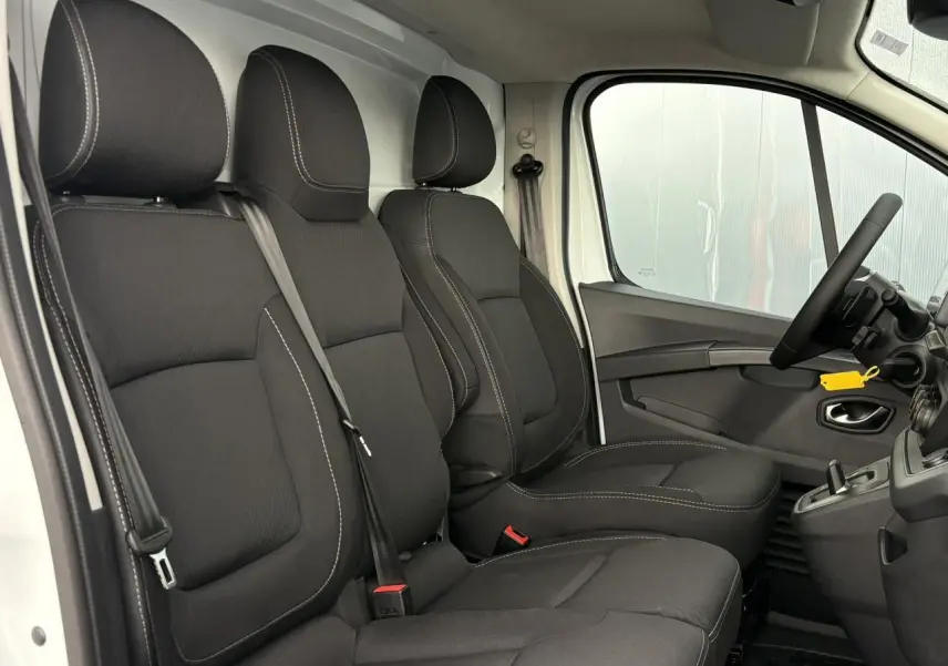 Vue intérieure côté conducteur du Renault Trafic Fourgon blanc, sièges tissu noir avec coutures contrastantes.