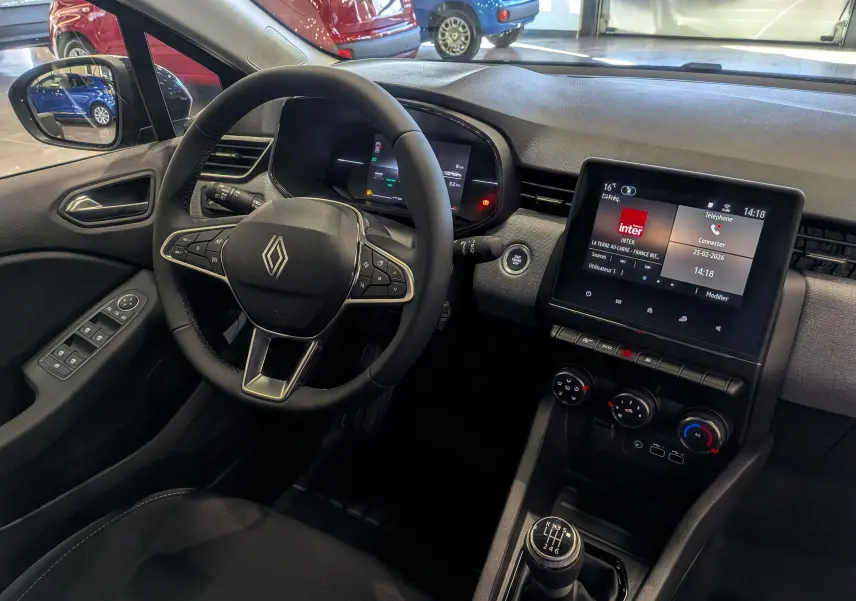 Vue intérieure côté conducteur de la Renault Clio V noire, avec volant multifonction, écran tactile et boîte manuelle six vitesses.