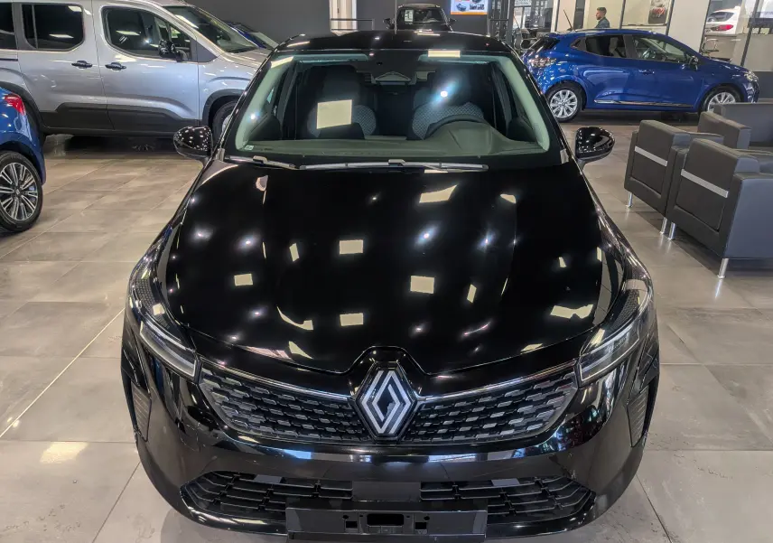 Vue avant d'une Renault Clio V noire 2025 en concession, mettant en valeur sa calandre et ses phares LED modernes.
