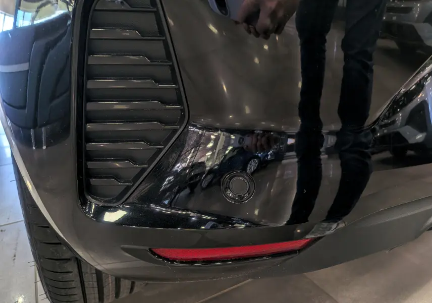 Détail du pare-chocs arrière droit noir de la Renault Clio V avec capteur de recul et feu réfléchissant.