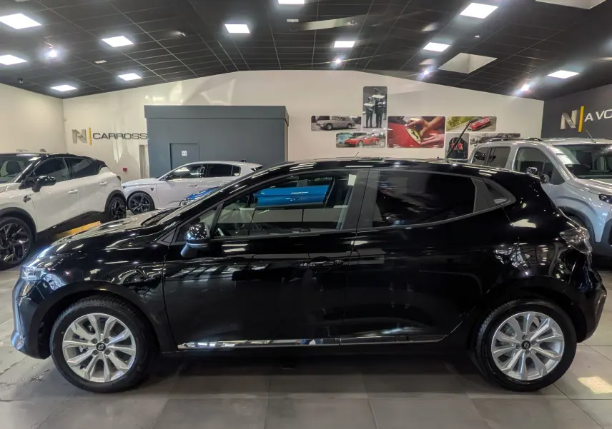 Profil côté gauche d'une Renault Clio V noire 2025 en intérieur, mettant en valeur sa silhouette compacte et ses lignes modernes.