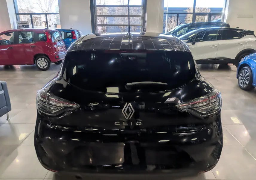 Vue arrière d'une Renault Clio V noire 2025 en intérieur, avec logo et feux arrière distinctifs visibles.