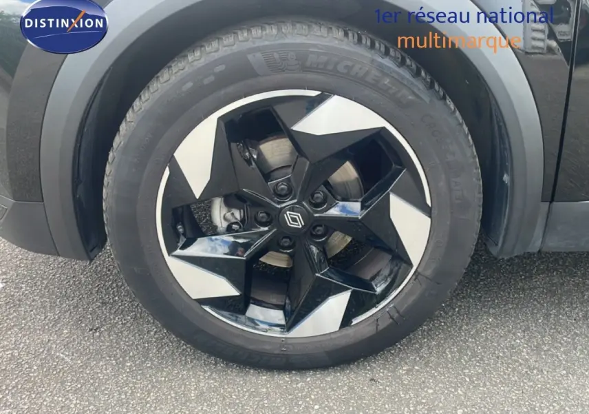 Gros plan sur la roue avant droite du Renault Captur noir étoile métal avec jante noire et argentée au design géométrique.