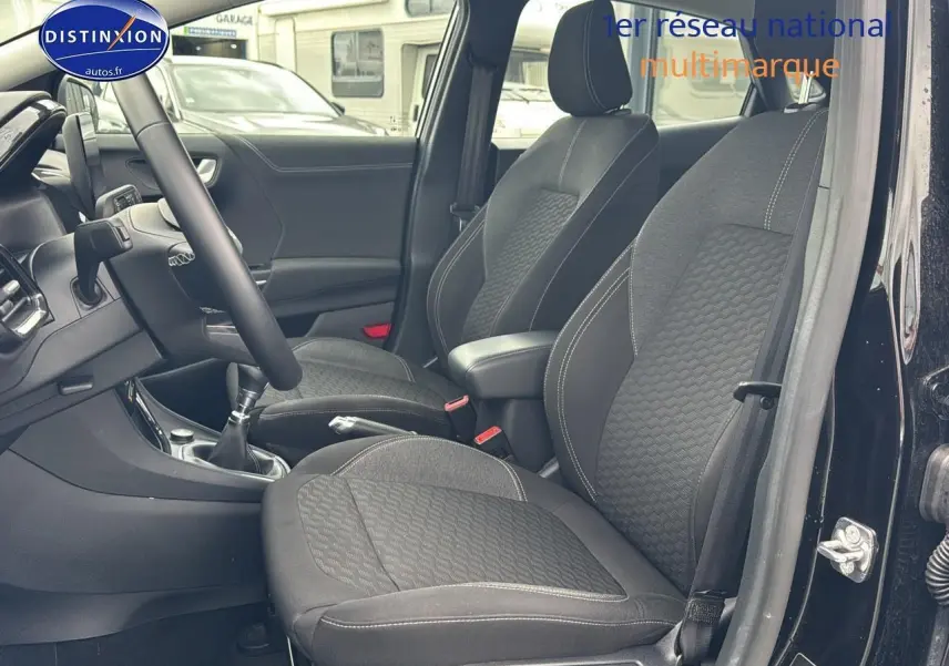 Intérieur avant du Ford Puma noir 2023, vue côté conducteur montrant sièges tissu noirs et console centrale avec boîte manuelle.