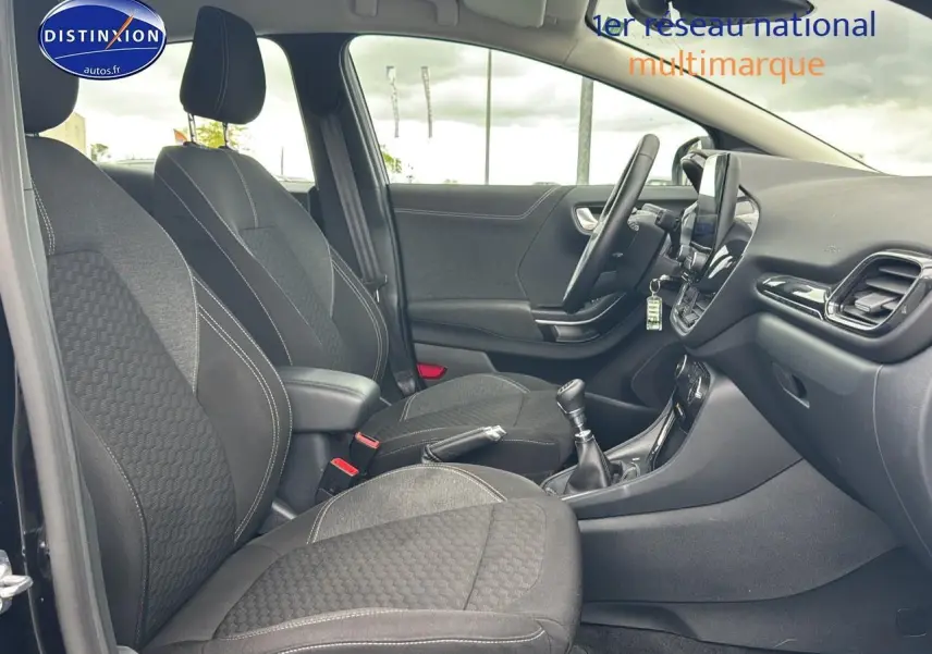 Intérieur avant du Ford Puma 2023 noir, vue côté gauche montrant sièges tissu noirs et console centrale avec boîte manuelle.