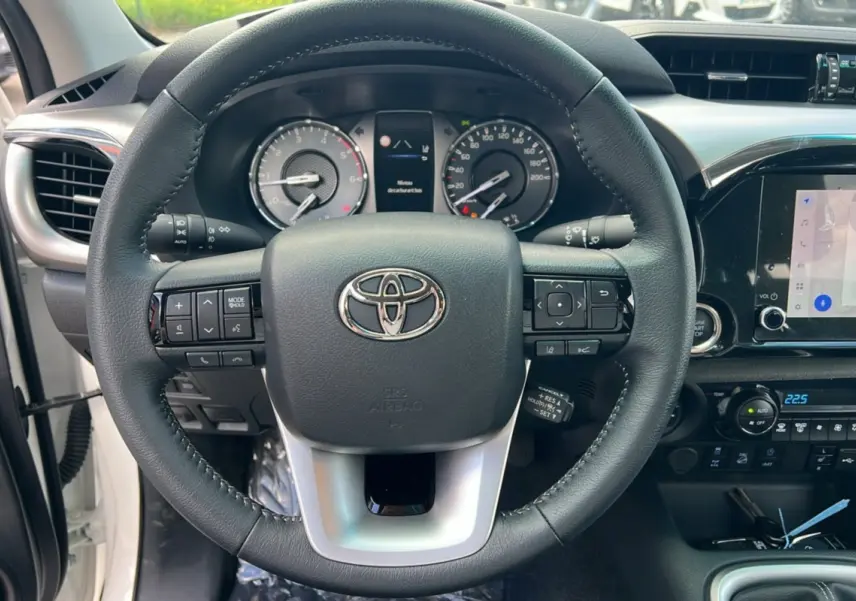 Vue rapprochée du volant et du tableau de bord du Toyota Hilux 2025, avec commandes intégrées et écran tactile.