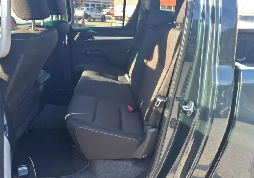 Vue côté droit arrière du Toyota Hilux 4x4 2025 vert métal, montrant la banquette arrière en tissu noir.