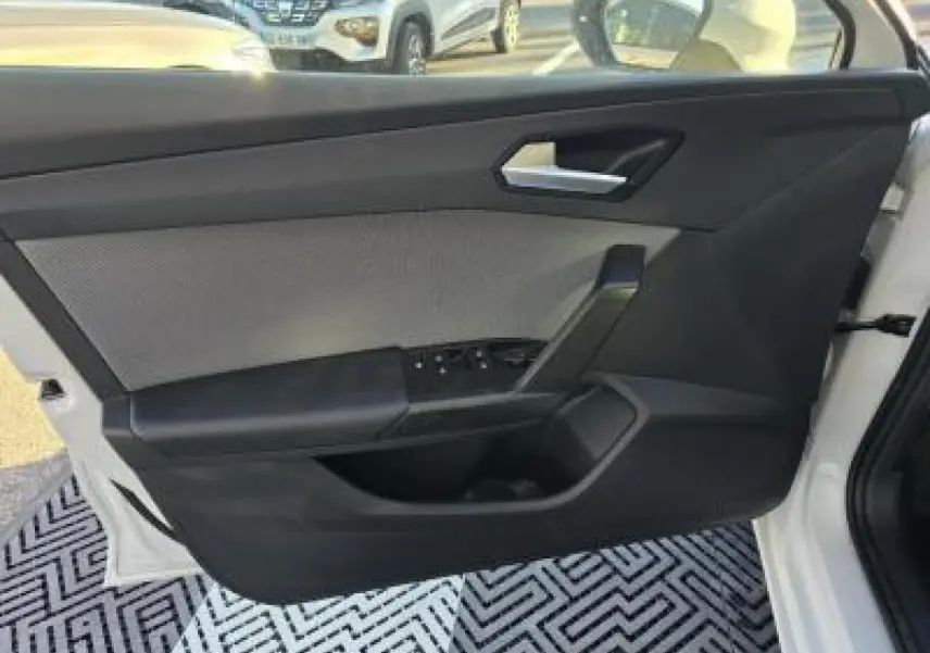 Porte côté gauche ouverte d'une SEAT LEON blanche 2024, montrant la garniture intérieure noire et les commandes de vitres.