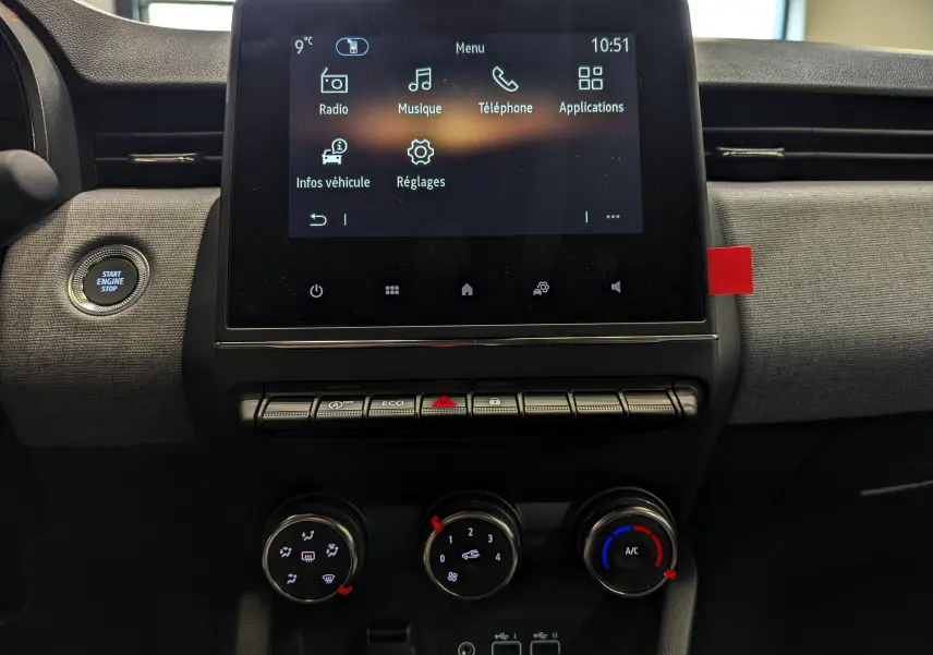 Vue rapprochée de la console centrale de la Renault Clio V 2025, écran tactile et commandes climatisation visibles.