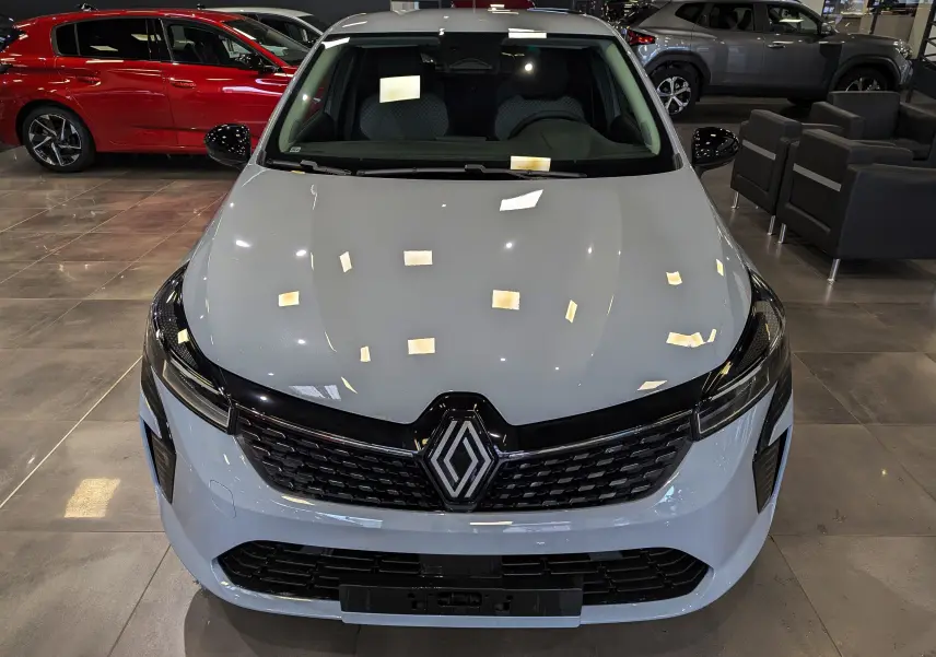 Vue avant d'une Renault Clio V gris Rafale avec calandre noire et logo Renault bien visible en concession.