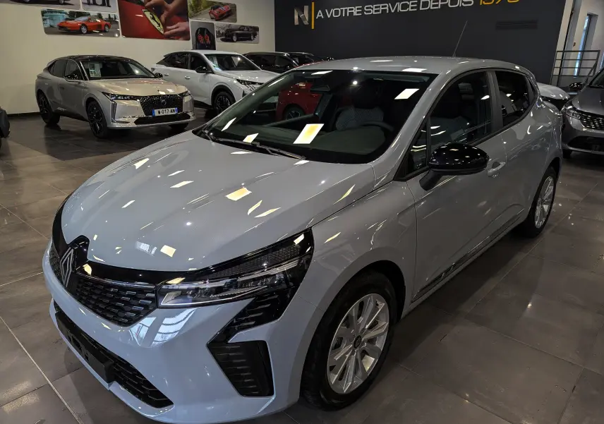 Renault Clio V Blue dCi 100 Gris Rafale en 3/4 avant droit, avec calandre noire et jantes alliage en showroom.