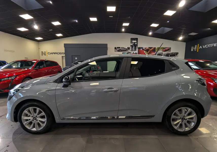 Profil côté gauche de la Renault Clio V gris Rafale en intérieur, avec jantes alliage et vitres teintées.