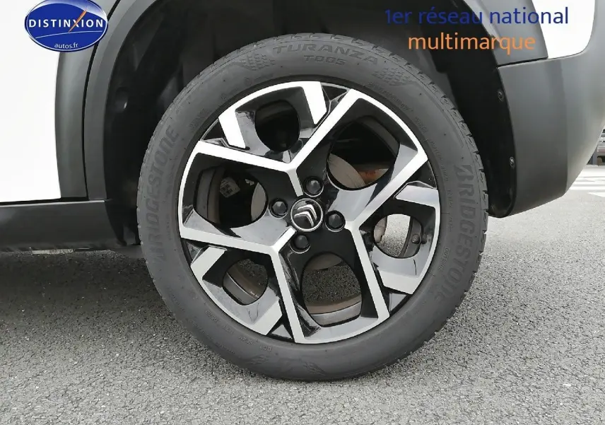 Gros plan sur la roue avant droite d'une Citroën C3 Aircross blanc polar, avec jante alliage noire et argentée.