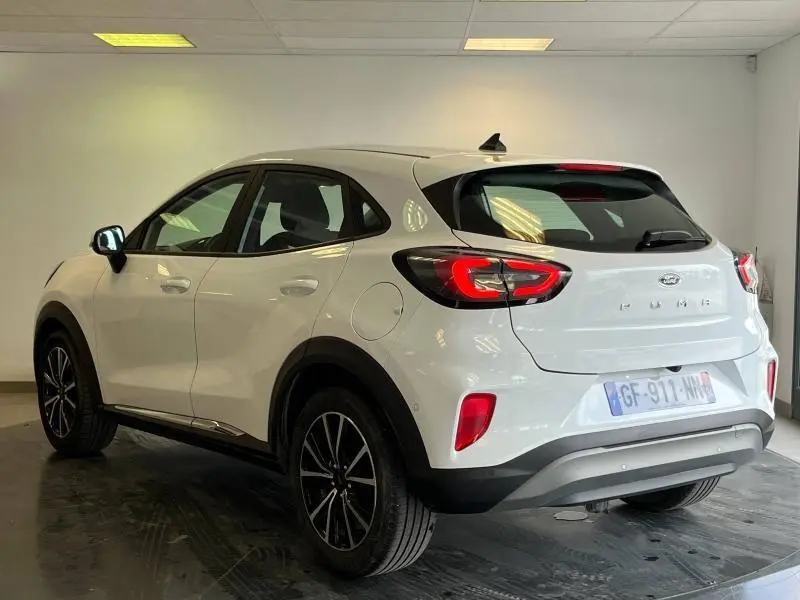 Vue 3/4 arrière droite d'une Ford Puma blanc glacier avec jantes alu et feux arrière LED dans un intérieur neutre.