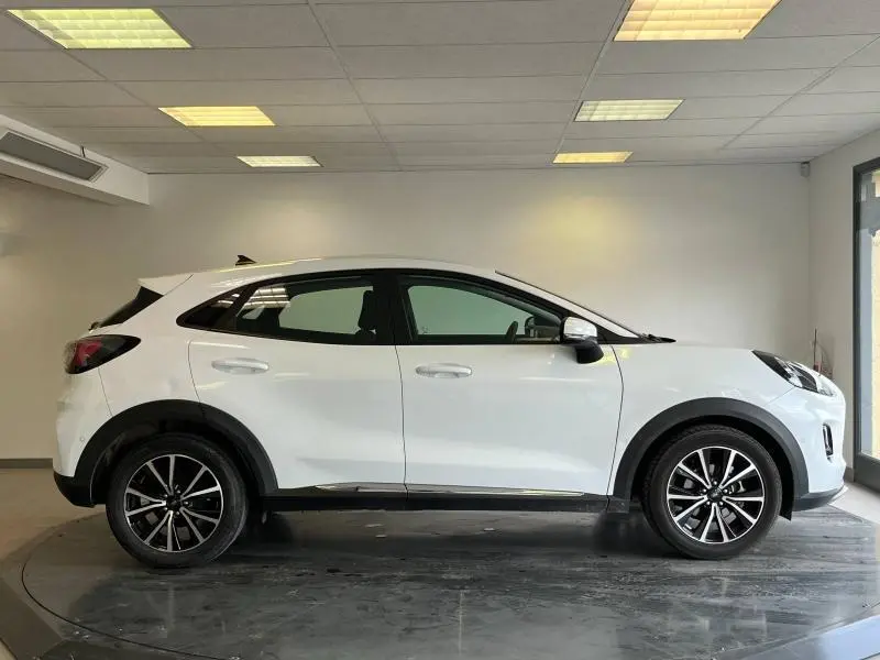 Ford Puma blanc glacier vu de profil côté gauche, avec jantes alliage et rétroviseurs noirs contrastants.