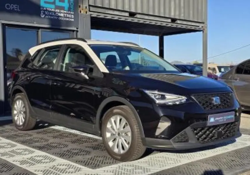 SEAT Arona 2024 noir minuit avec toit blanc, vue 3/4 avant mettant en valeur ses jantes alliage et calandre distinctive.