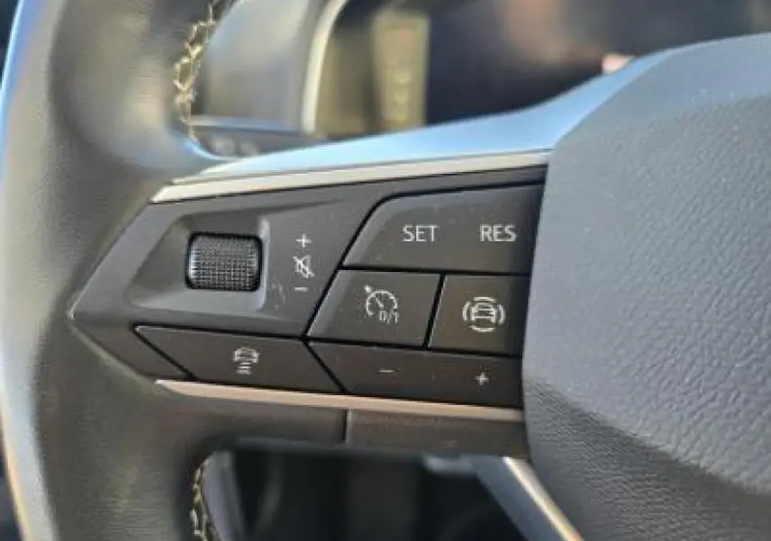 Gros plan sur les commandes du volant cuir multifonction du SEAT Arona 2024, boutons de régulateur de vitesse et assistance.
