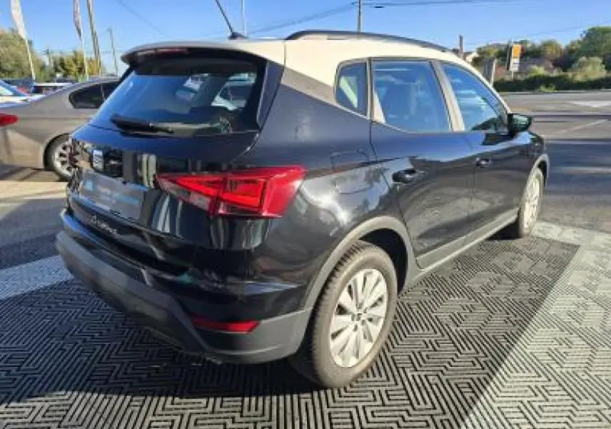 SEAT Arona 2024 noir minuit avec toit contrasté, vue 3/4 arrière côté gauche sur parking extérieur.