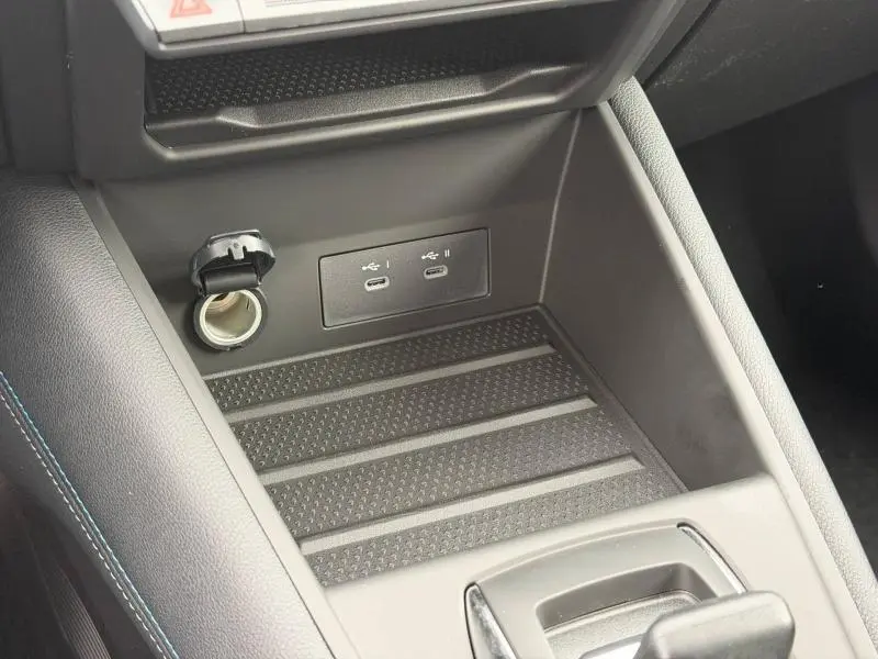 Vue rapprochée de la console centrale du Renault Captur 2026, avec prises USB-C et prise 12V, finition intérieure noire avec surpiqûres bleues.