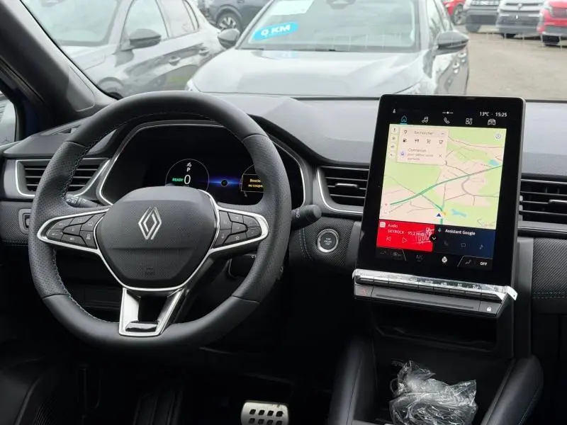 Vue intérieure frontale du tableau de bord et volant du Renault Captur 2026 hybride avec écran tactile vertical.